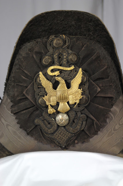 The large decorative detail of a chapeau Before treatment photo of military chapeau c. 1832. The hat would be conserved by textile expert Gwen Spicer at Spicer Art Conservation. SAC conserves and preserves military antiquities, collectibles and memorabilia