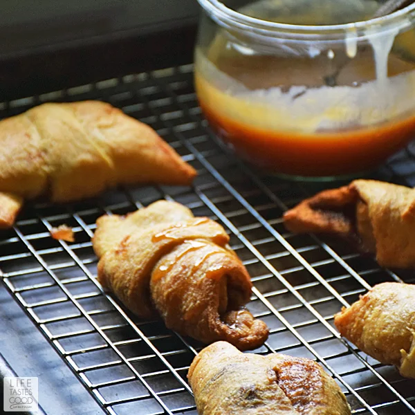 Crescent roll apple turnovers on a baking rack drizzled with caramel sauce and ready to serve