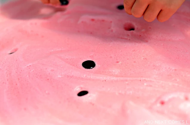 Close up of pink soap foam and black seeds in a watermelon sensory activity for kids