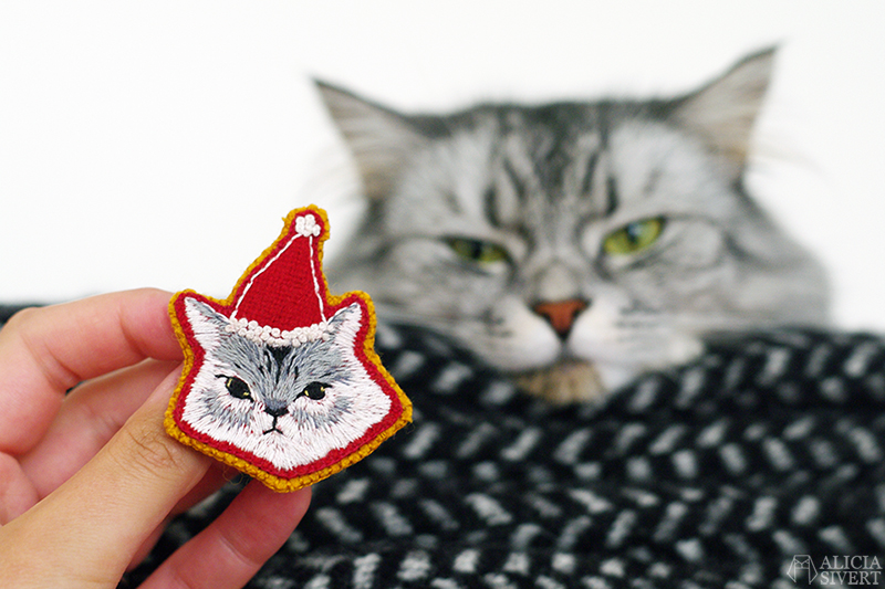 Lussekatt, broderad brosch av katt i tomteluva, av Alicia Sivertsson. / Embroidered Christmas cat brooch by Alicia Sivertsson. aliciasivert alicia sivert sivertsson broderi broderier embroidery hand needlework fritt skapa skapande kreativitet konst textil textilkonst schattérsöm broderad brosch embroidered brooch christmas cat julkatt jul katt tomteluva lussekatt