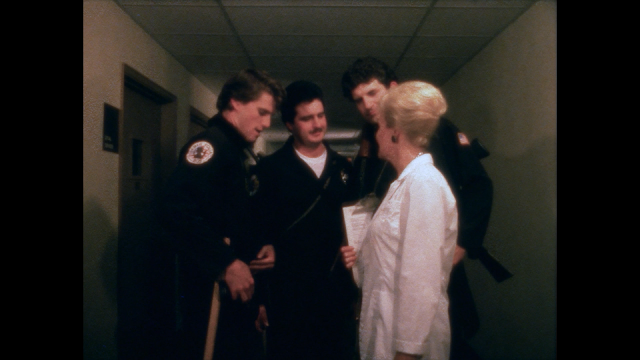 three cops talk to a nurse in a hallway