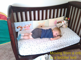 toddler boy smiling while laying down on his toddler bed  Text: Moving from a crib to a toddler bed