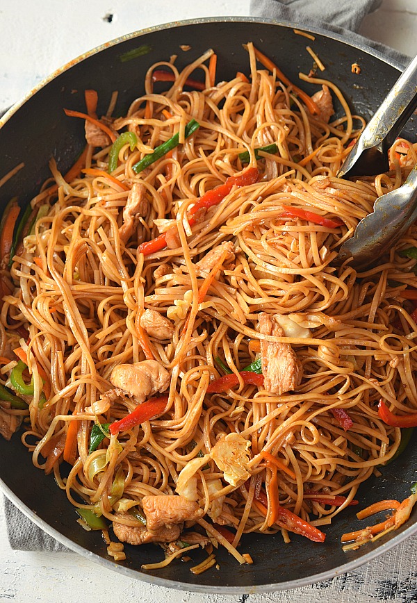 Chicken Lo Mein! Delicious soft juicy Chicken cooked along with vegetables like Red Bell Peppers,Spring Onions,Garlic,Ginger,Onion,Carrot and Cabbage tossed together with Egg Noodles in sauces made from Soy Sauce,Sriracha and Oyster sauce! Delicious dinner/lunch sorted under 10$ #savorybitesrecipes #chickenlomeinrecipe #betterthantakeout #deliciousfood #homemade a top look of a pan with delicious chicken lo mein