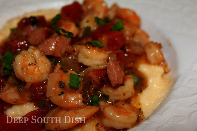 Shrimp and Sausage cooked in a spicy tomato, roux and trinity enhanced sauce, and served on a bed of Garlic Cheese Grits.