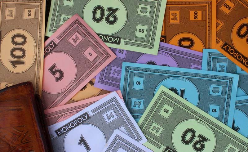 Monopoly notes spread next to a wallet.