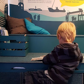 5 Ausflüge mit Kindern in Kiel bei Regenwetter. Bei Schlechtwetter machen die Kinder es sich in der Bücherecke des Schifffahrtsmuseums Kiel gemütlich.