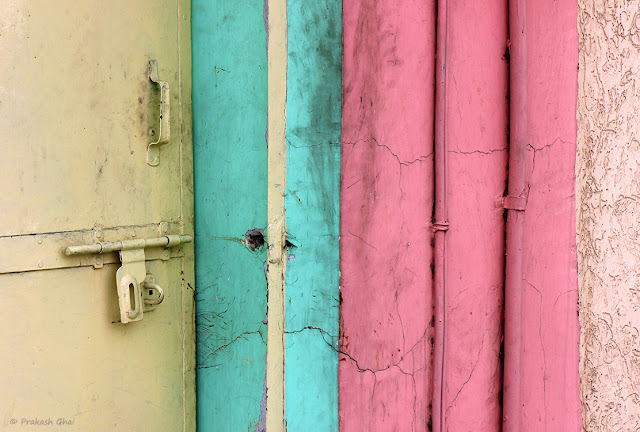 Unlatched Yellow Door adjacent to Green and Pink Wall.