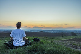 Young boy meditating in a field, facing horizon