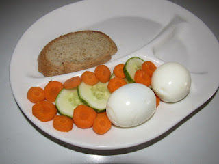 A plate of eggs, carrot pieces, cucumber and bread to help with my weight
