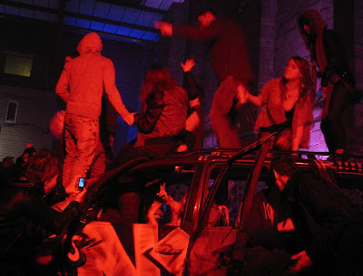 Party-goers swarm over a scrap car