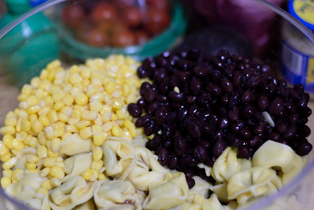Corn, black beans, and tortellini in a mixing bowl. 