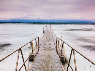 A winter time scenic of dock extending into frozen water at Thousand Islands National park Captured by Chris Gardiner Photography www.cgardiner.ca