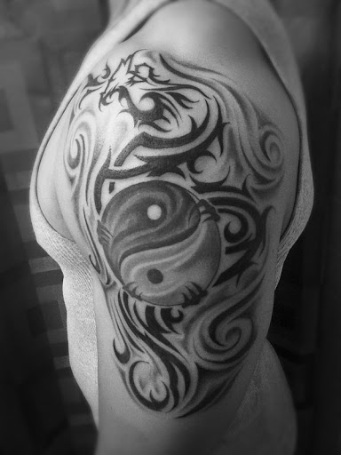 Braço Yin Yang tatuagem. Esta tatuagem é acompanhado por vários desenhos tribais para realçá-lo formando um dragão como o da figura carregando o símbolo em seus pés.