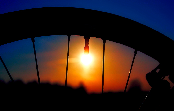 Dwumilowe koła - fragment koła rowerowego na tle zachodzącego słońca