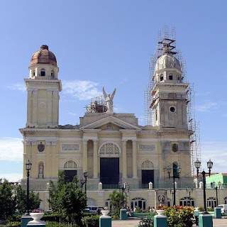 Santiago de Cuba, Catdral de Nuestra Señora de Asunción. Santiago de Cuba, Catedral de Nuestra Señora de Asunción. Die gelb angestrichene Kathedrale wirkt neoklassizistisch, zwei Türme, der rechte eingerüstet, über dem großen mittleren Tor ein geflügelter Erzengel.