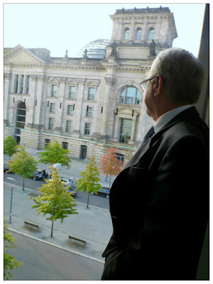 Ein Mann im Anzug und mit grauen Schläfen blickt aus einem höheren Stockwerk des Abgeordnetenhauses auf den Reichstag.