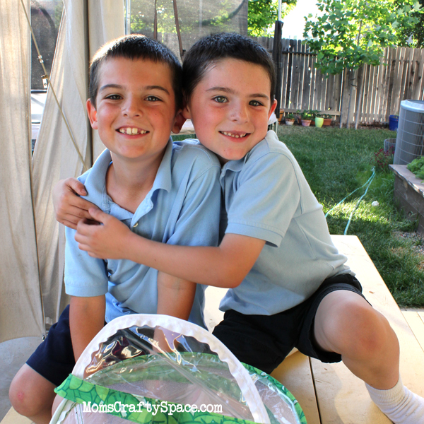 brothers outdoors hugging next to butterfly experiment for kids