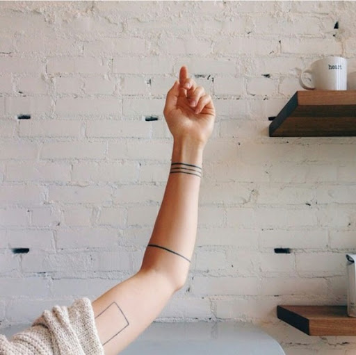 Três linhas pretas funcionam como uma pulseira, enquanto uma única linha preta funciona como um antebraço banda neste tatuagem conjunto.