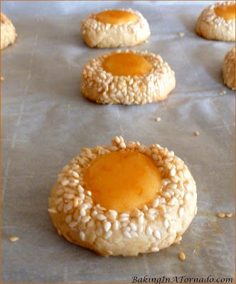 Orange Sesame Thumbprint Cookies, sesame studded cookies filled with an orange jam and powdered sugar center. A fun alternative to the original cookie flavors. | Recipe developed by www.BakingInATornado.com | #recipe #cookies