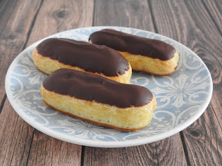 3 mini eclairs on a blue and white plate