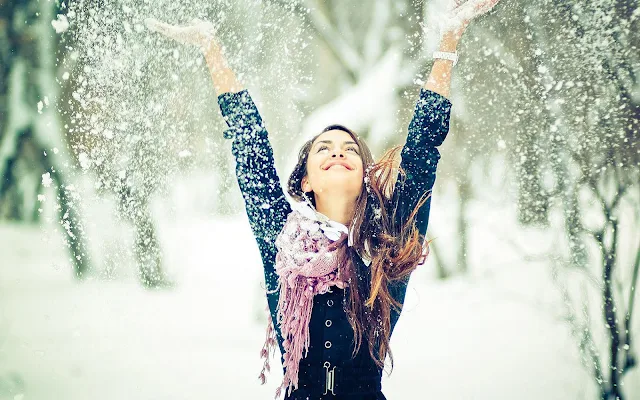 Vrouw gooit sneeuw in de lucht van blijdschap
