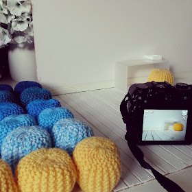 Group of dolls' house modern miniature pouffes, next to a miniature room setup and a camera ready to photograph it.