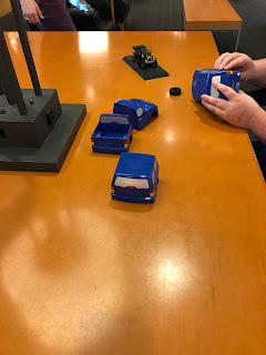a set of hands working with small plastic parts of an automobile model