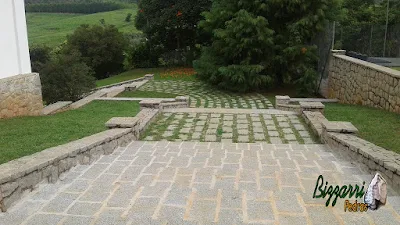 Revestimento com pedras rústicas em mureta de pedra com escada de pedra, o muro de pedra com pedra folheta, o piso de pedra com junta de grama em sede de fazenda em Atibaia-SP.