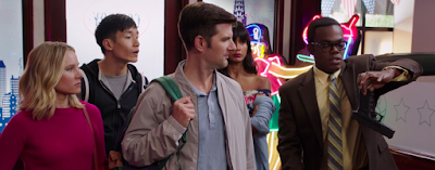 From left: Eleanor, Jason, Trevor, and Tahani all look at Chidi, who is holding the base of a gun between his thumb and forefinger