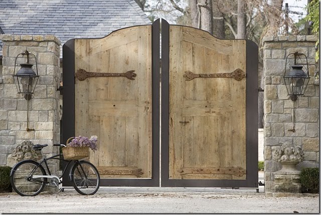Breathtaking and massive wood doors and charming bicycle at entrance of European inspired home (found on Hello Lovely)