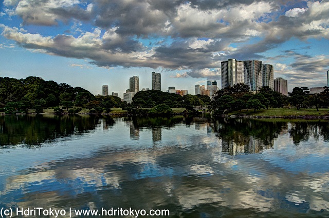 pond and white cloud with reflection on water. skyline of Shiodome district in background
