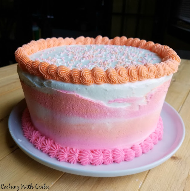 Special occasion cookies just went to the next level! Layers of cookie and plenty of frosting, making it perfect for a celebration! whole cake that looks like regular birthday cake with pink and orange frosting, but it's really giant cookies inside
