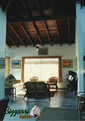 Vista da sala de estar com o piso de cimento queimado branco com o forro de madeira de Ipê por cima dos caibros e nas paredes a massa de mão única desempenada e filtrada em construção de casa em Ubatuba-SP.