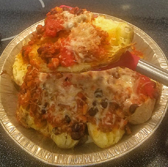this is a chili topped baked potatoes loaded with shredded cheeses, olives, sour cream and chopped tomatoes