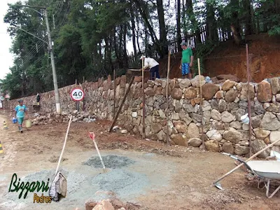 Construção do muro de pedra bruta sendo o tipo de pedra moledo com cores variadas sendo tipo de muro de pedra com junta seca sem massa nas juntas. Muro de pedra na cidade de Joanópolis-SP.