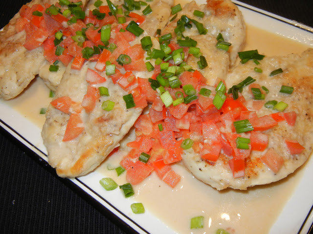 Chicken Pomodoro with tomatoes, green onions, and cream sauce on a white plate 