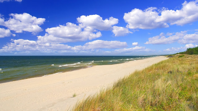 Een prachtig strand met blauwe lucht en witte wolken ergens in Nederland.