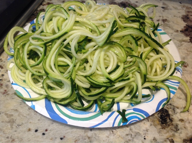 spiralized green zucchini on a paper plate
