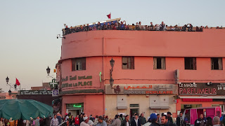main square of Djemaa El Fna is covered with tourists which glimpse on the roof tops over the square