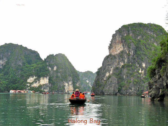small boats with tourists visiting a small village on Halong Bay