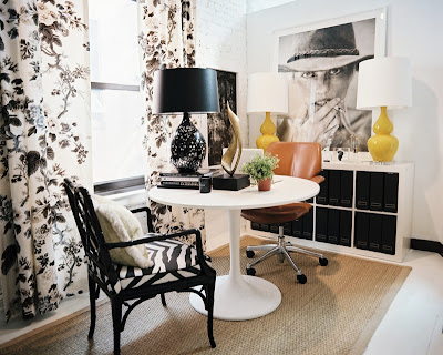 City office with white painted brick walls, Schumacher's Pyne Hollyhock chintz curtains,  Saarinen tulip table, a black painted faux bamboo chair and a yellow table lamp