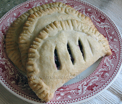 A close up photo of two cherry hand pies resting on a red and white plate.