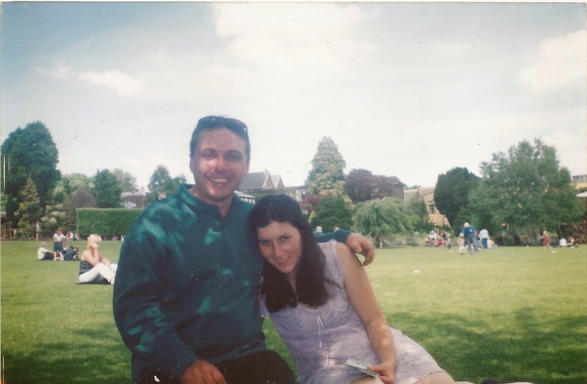 Couple sitting on grass in a picnic area. 