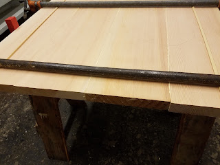photo of tabletop boards being glued and clamped together