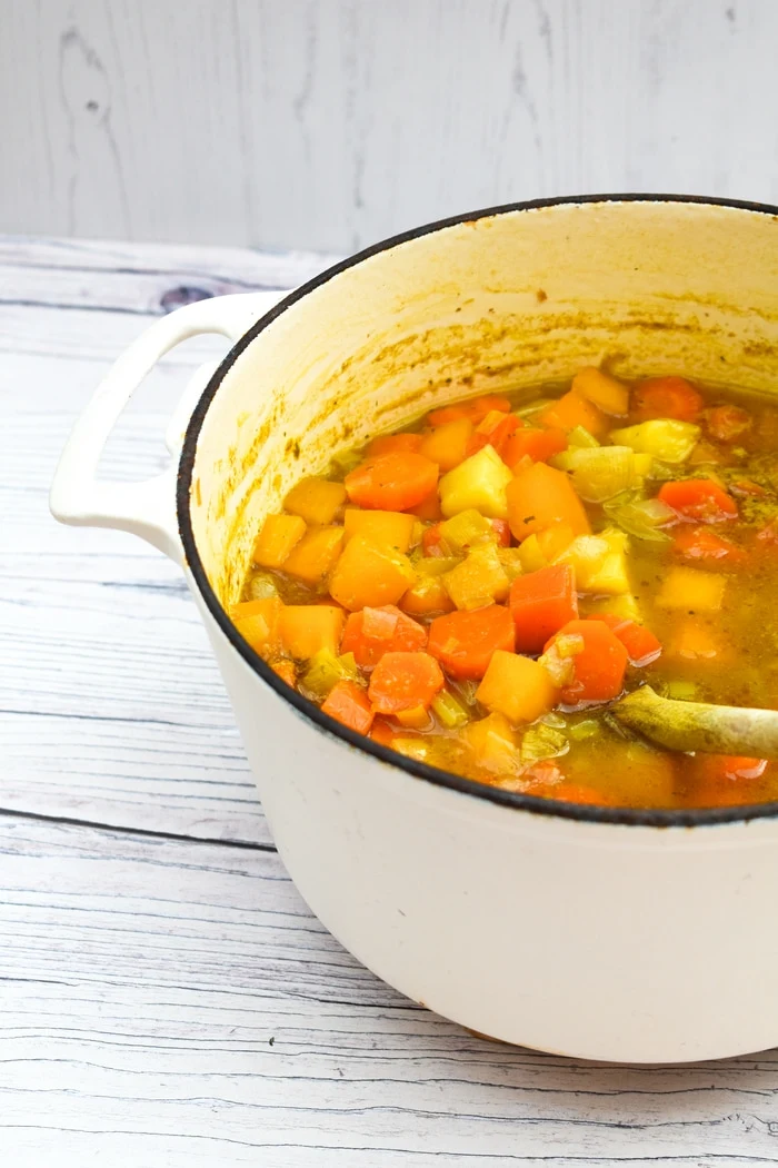 A large white cast iron pot full of Summer Root Vegetable Soup