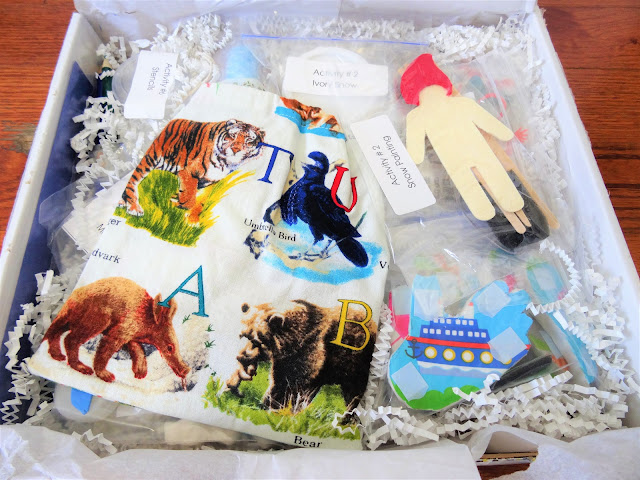 A small wooden effigy of a man, a foam animal print, a cloth pouch with animals on it, and other items in labeled sandwich bags.