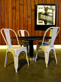 A dolls house miniature scene of four Xavier Pauchard Model A chairs around a cafe table.