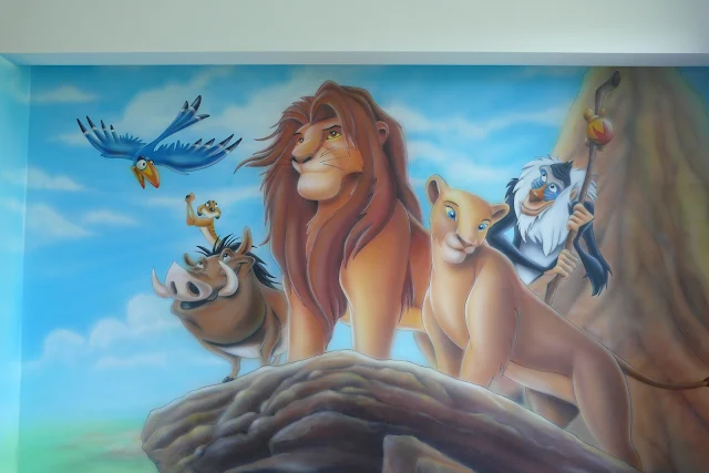 Malowanie na ścianie motywu z bajki Król Lew, grafiiti w pokoju chłopca