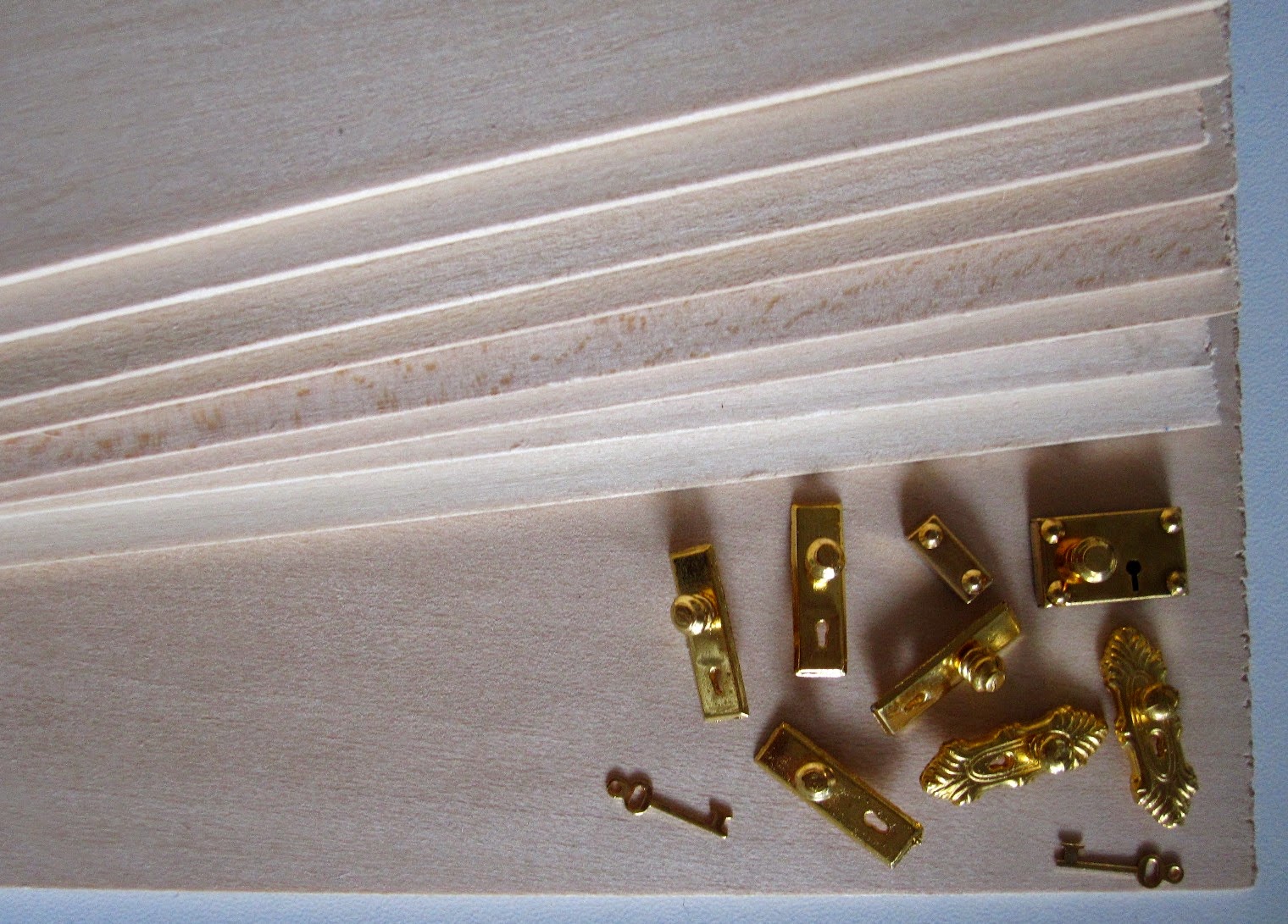Selection of miniature dolls house door handles on a stack of basswood lengths.