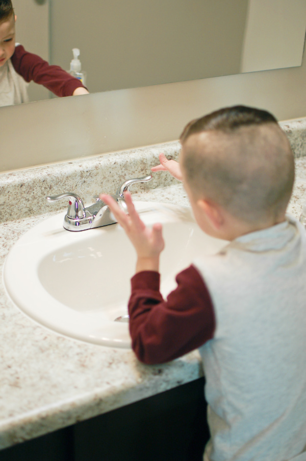 Little boy turns on the faucet to wash his hands after potty training